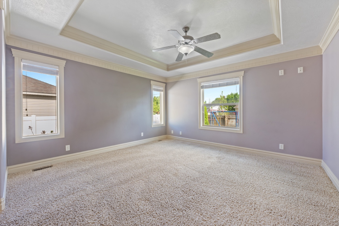 Primary bedroom with tray ceiling and natural light